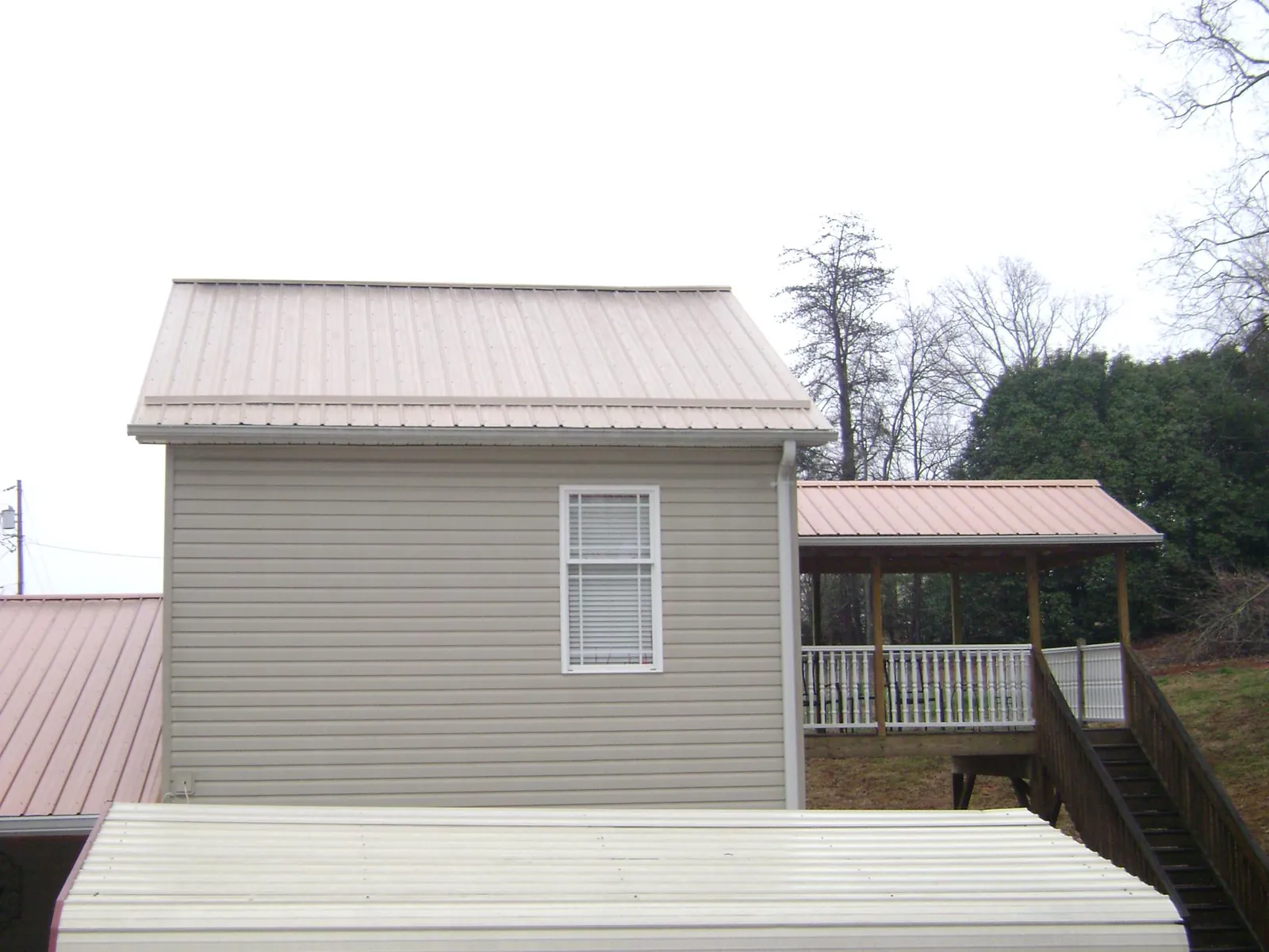 Tan metal roofs on a two story addition and attached porch, from a Roof Replacement job in West Lebanon